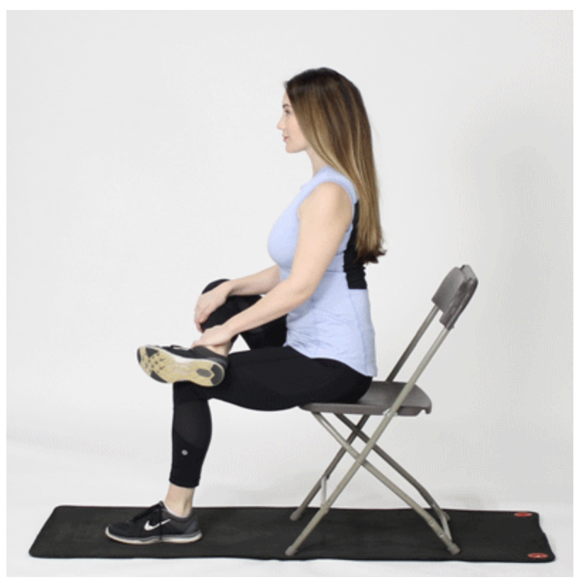 Person sitting cross-legged on a mat, stretching their glutes in a seated position.