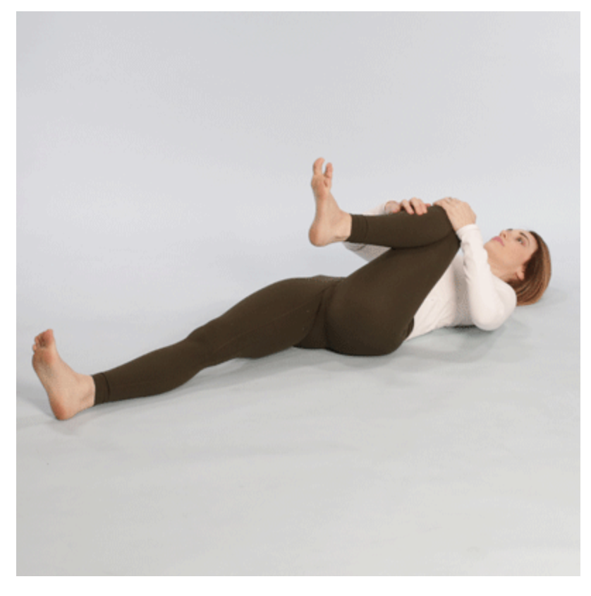 The knee to opposite shoulder stretch is performed by lying on your back and bringing your knee towards the opposite shoulder.